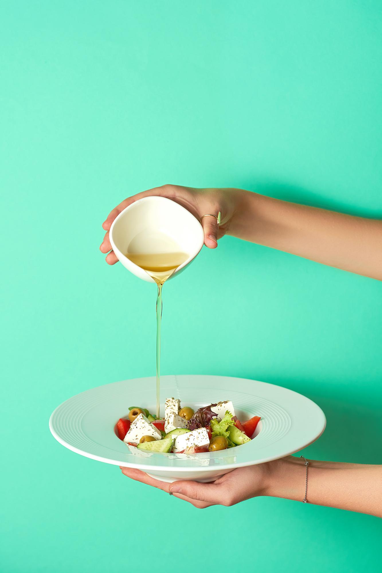 Hands plating a simple salad with vinaigrette